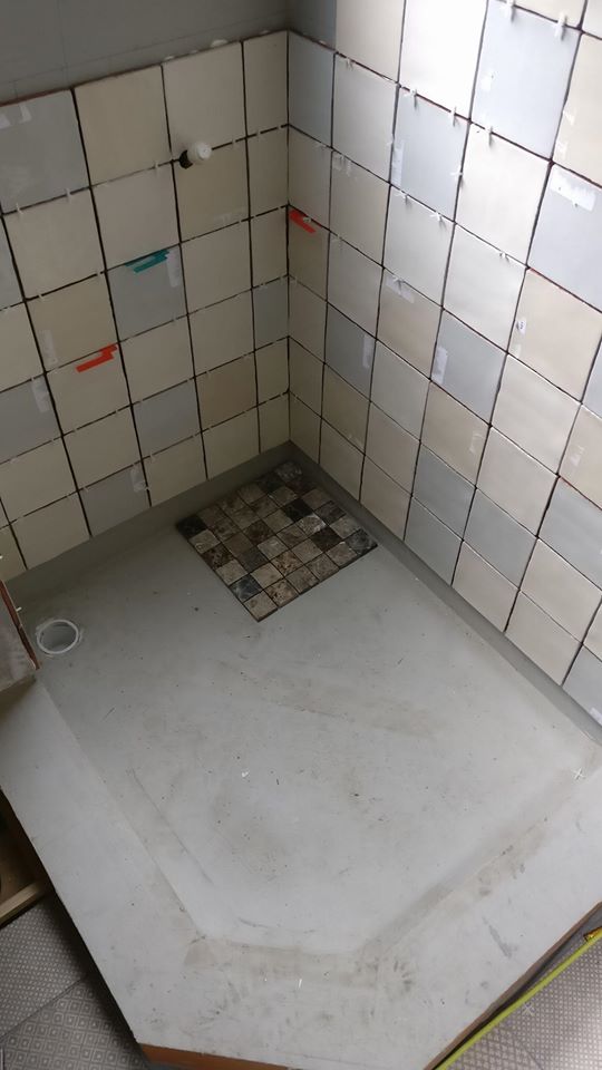 part tiled shower enclosure with blue tanking showing beneath